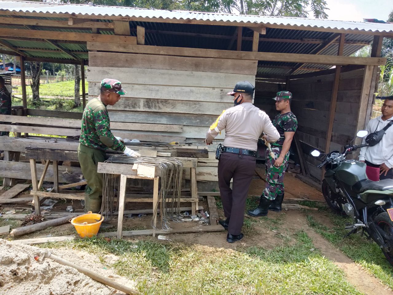 Babinsa dan Bhabinkamtibmas Merakit Besi Sebagai Kerangka Pembuatan Drainase